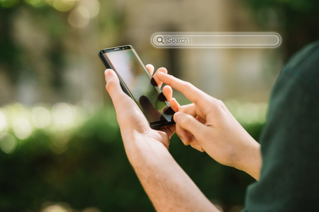 Hand hält Smartphone und eingeblendeter Balken für Suche.